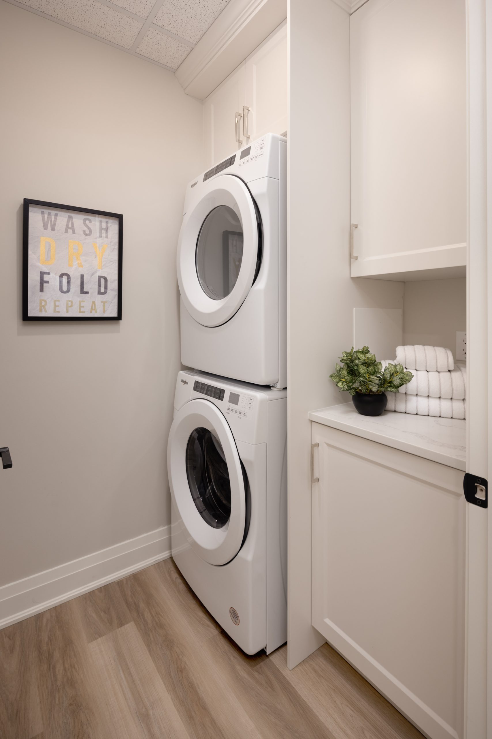 laundry room with stacked washer/dryer with built-in custom white cabinets.