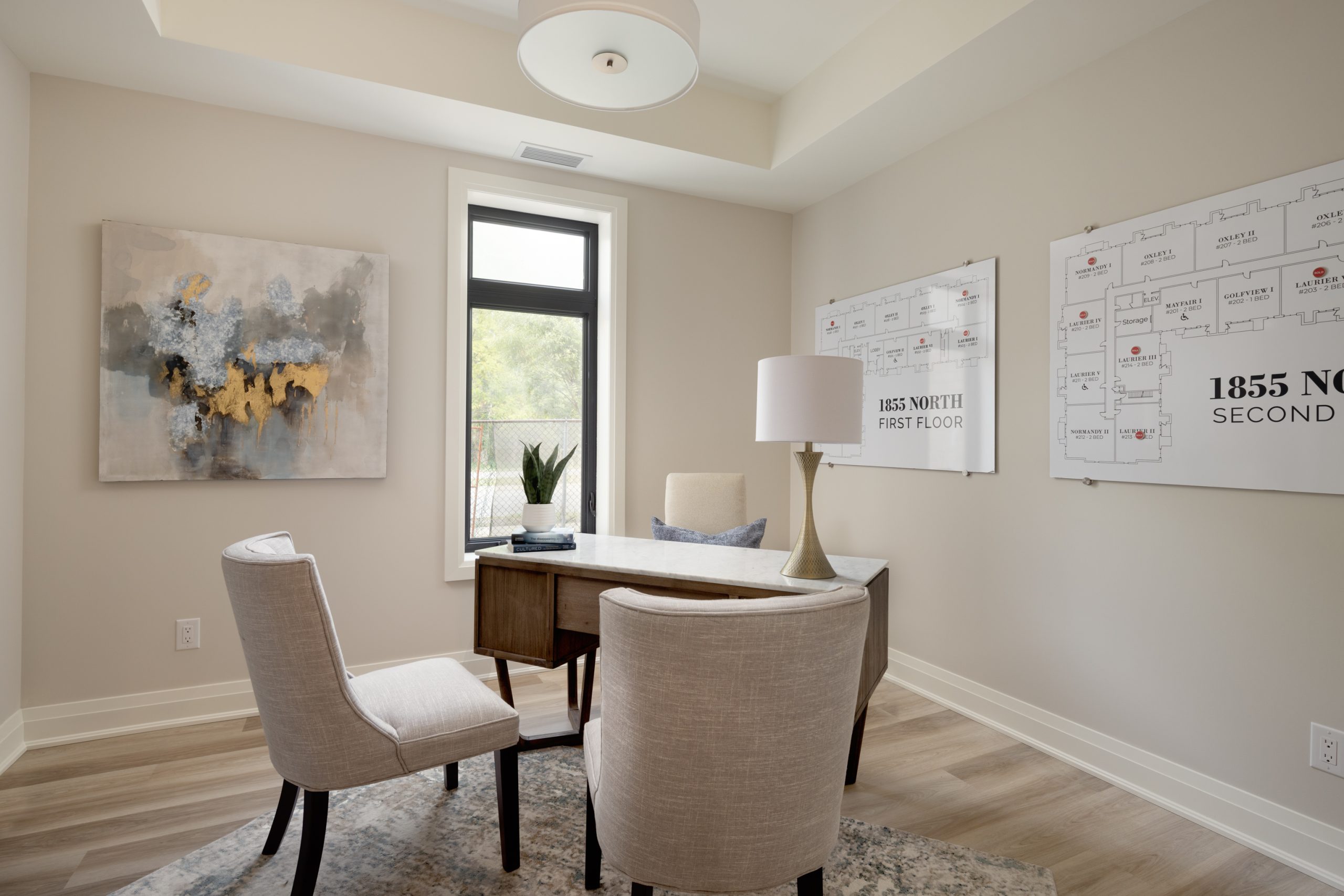 Home office featuring desk and 2 chairs. Floorplans for the homes are show on the wall.