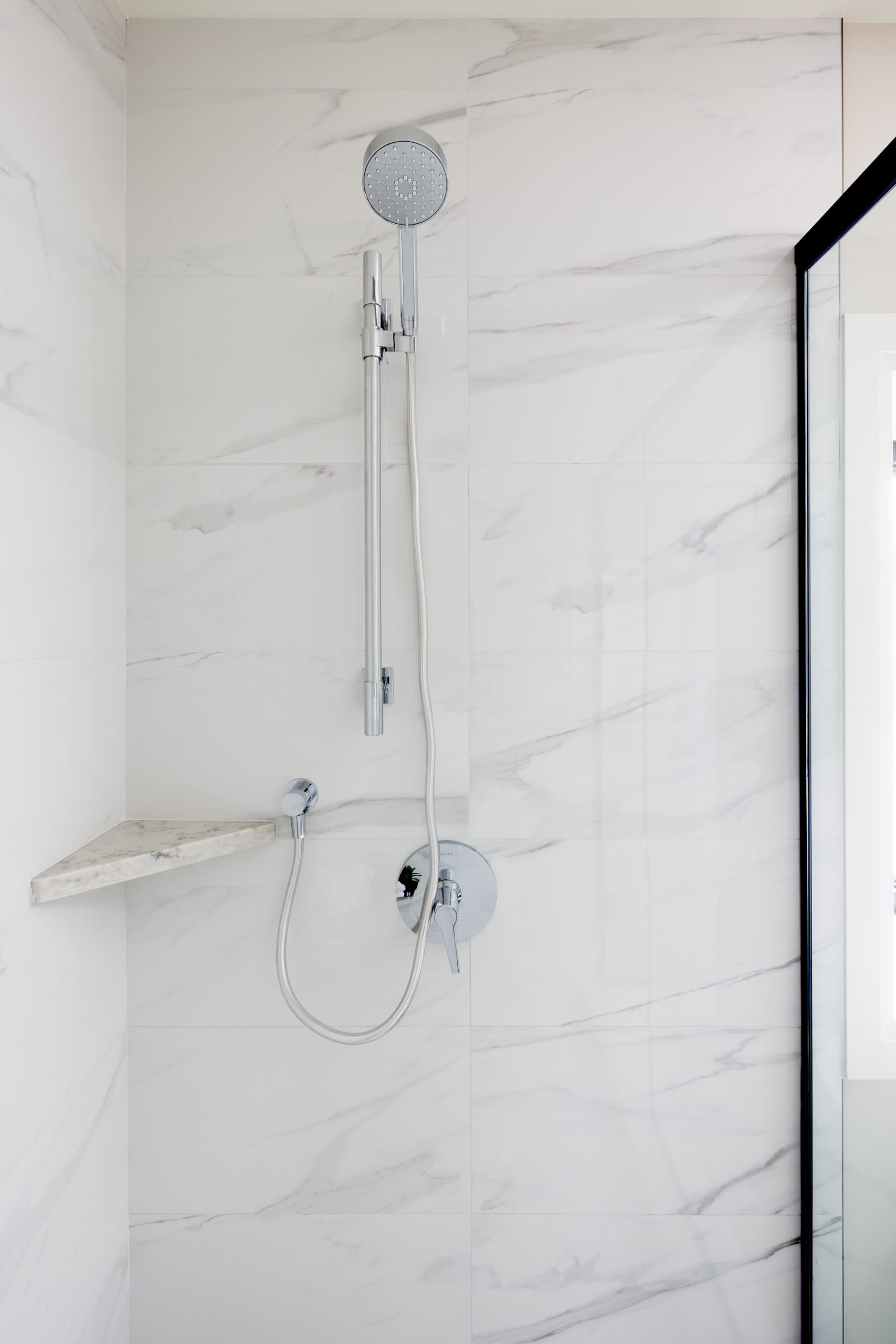 stainless steel shower head in marble tiled custom shower